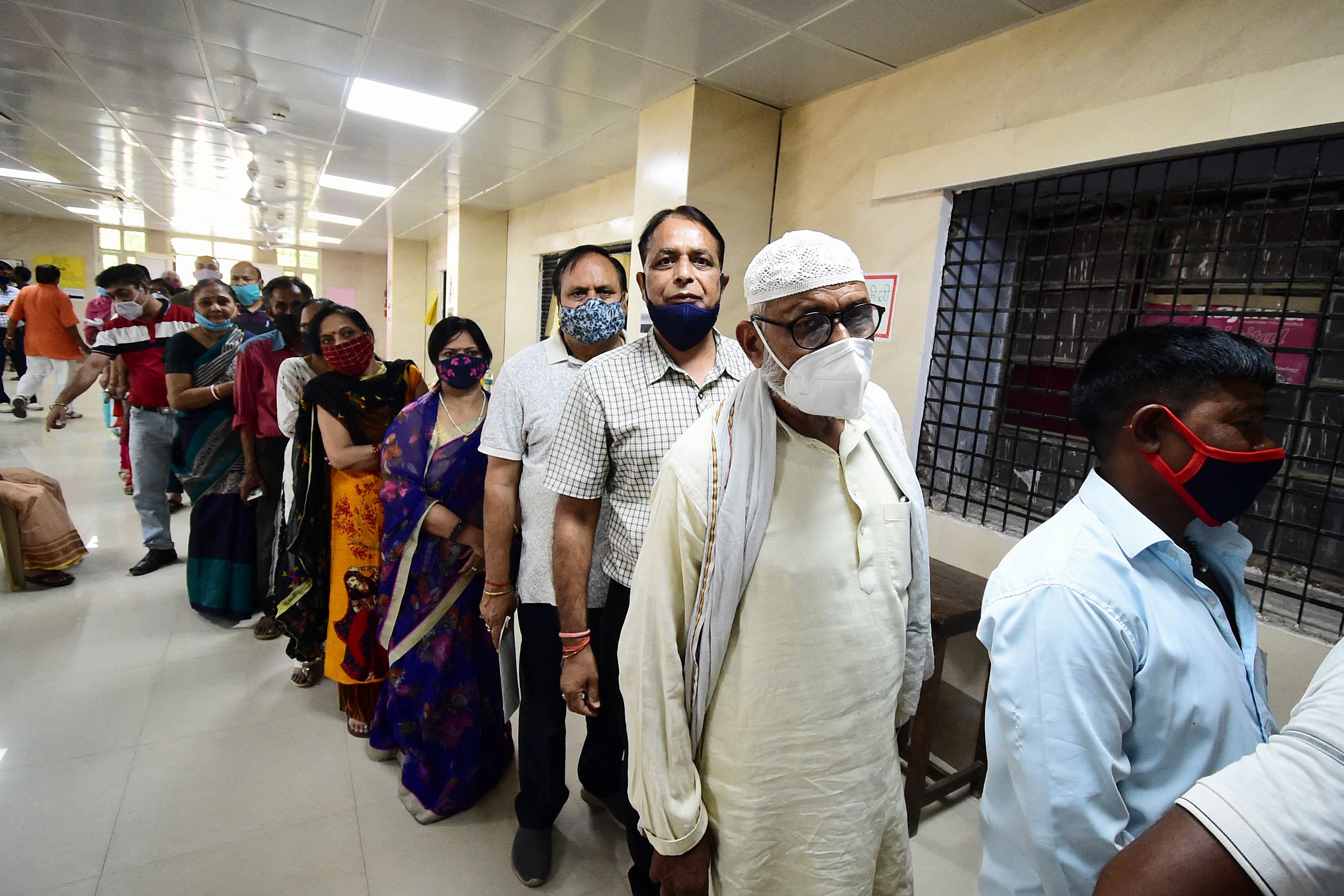 People stand in a queue to get inoculated with the COVID-19 coronavirus vaccine at Moti Lal Nehru Medical College in Allahabad.