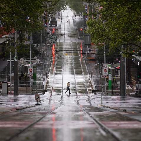 Lone person crosses tram tracks on Bourke Street in Melbourne