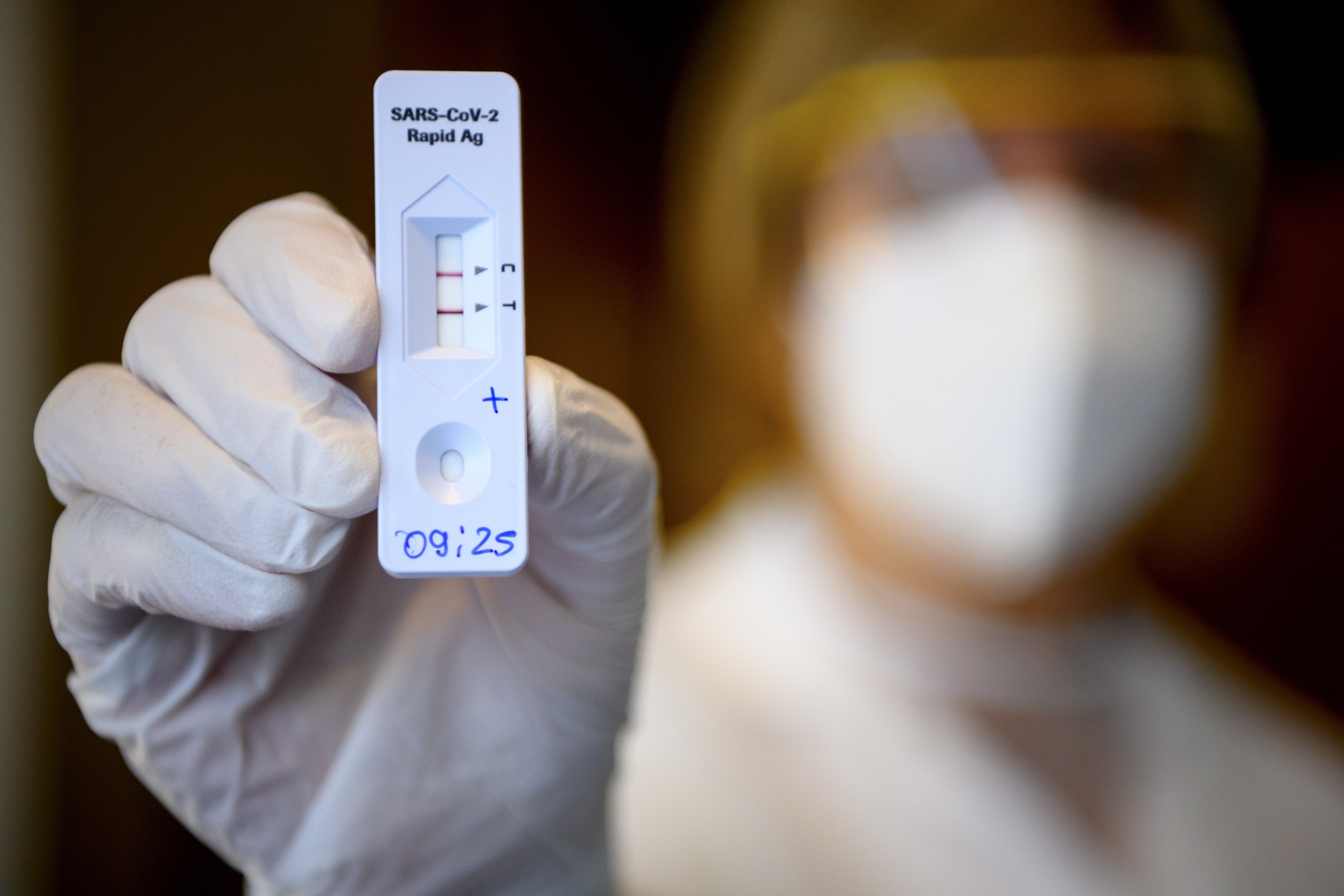 A health worker shows a positive SARS-CoV-2 Rapid Antigen Test from the Swiss multinational healthcare company 