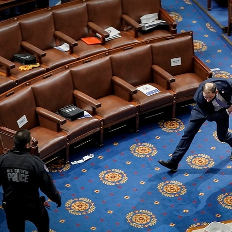 A police officer rushes a member of the House of Representatives to safety during the Jan 6 insurrection