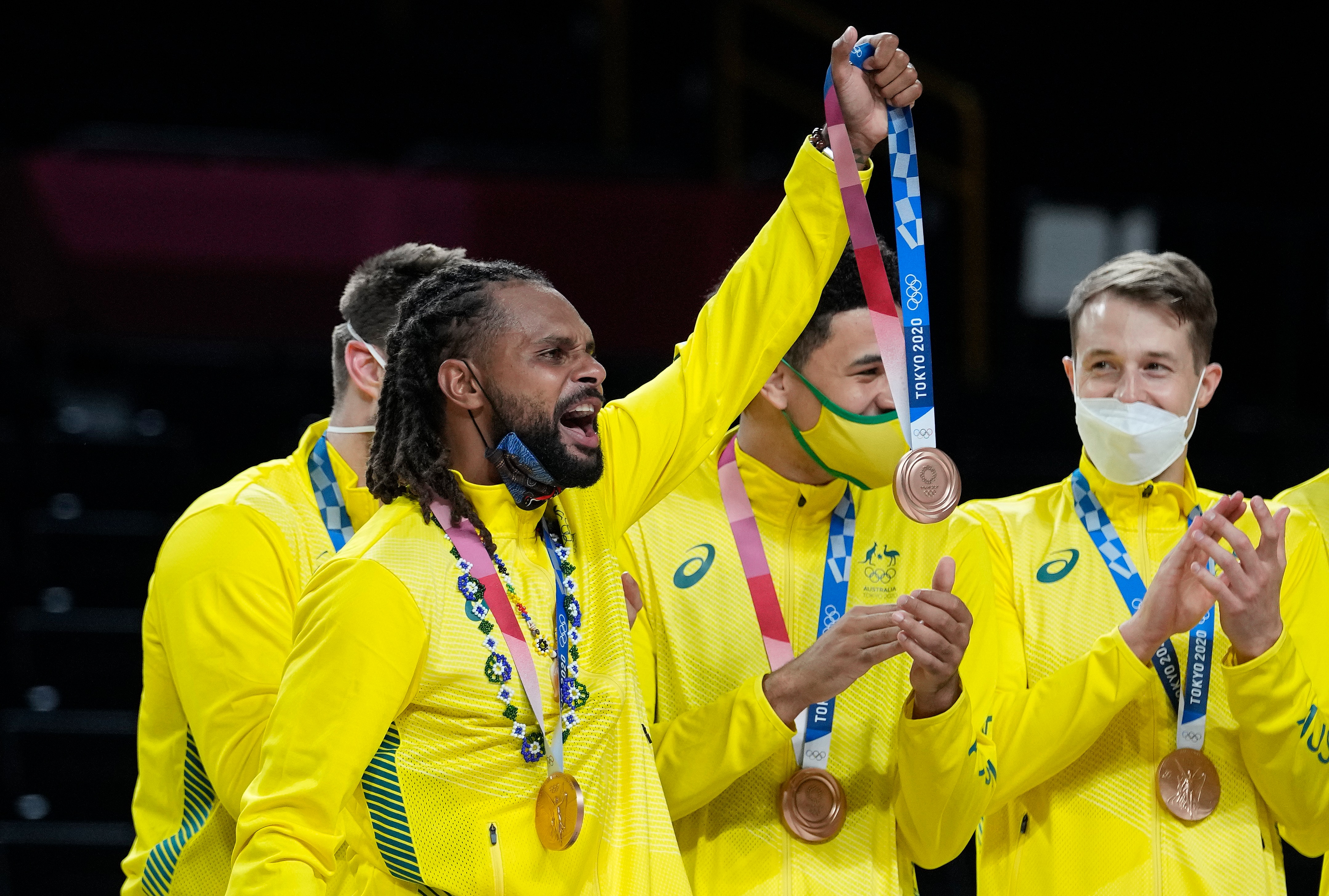 Australia's Patty Mills holds up a bronze medal for a teammate who was injured after beating Slovenia in the mens bronze medal basketball in Tokyo.