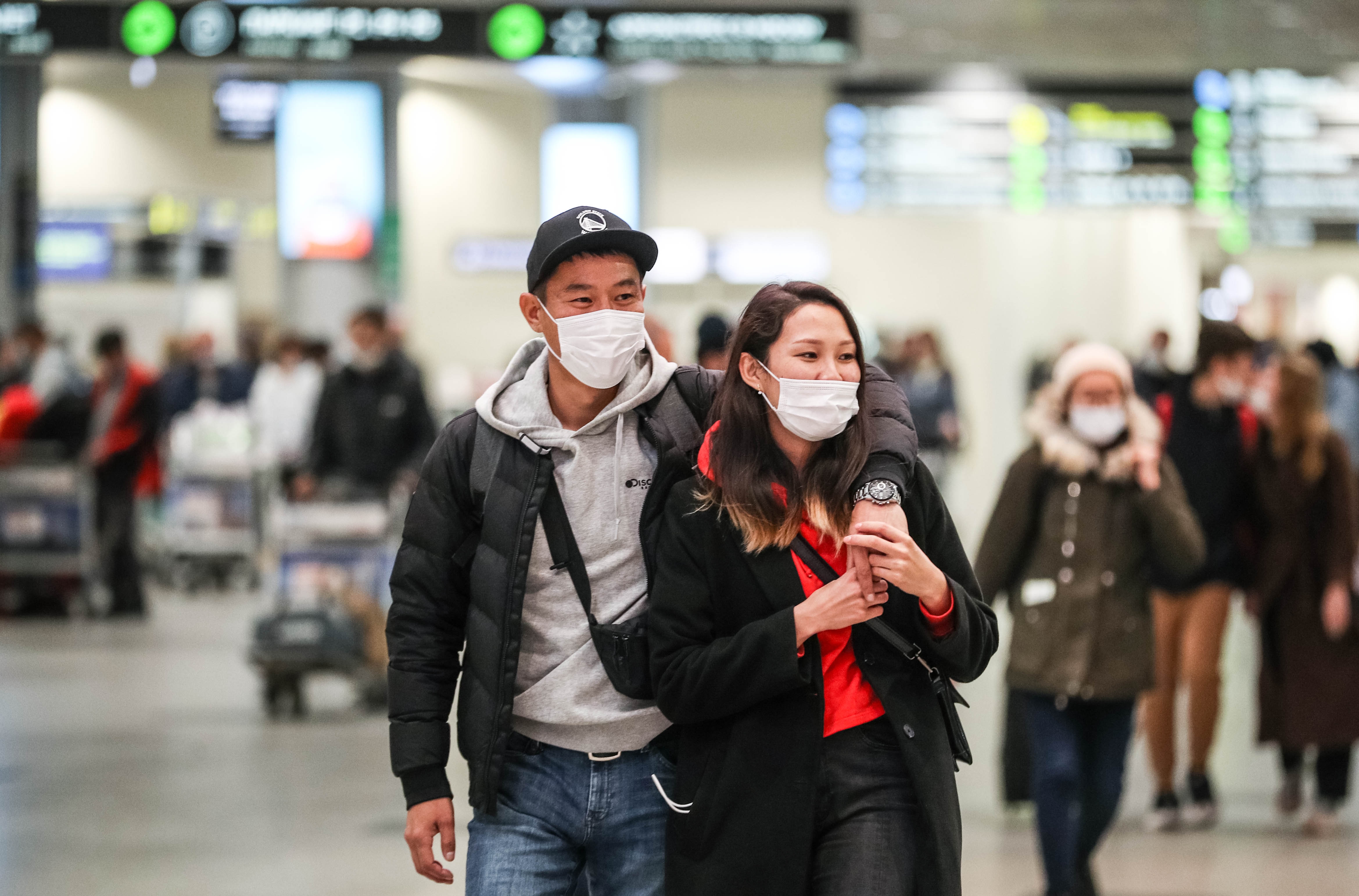 Two travellers wearing face masks at an airport. 