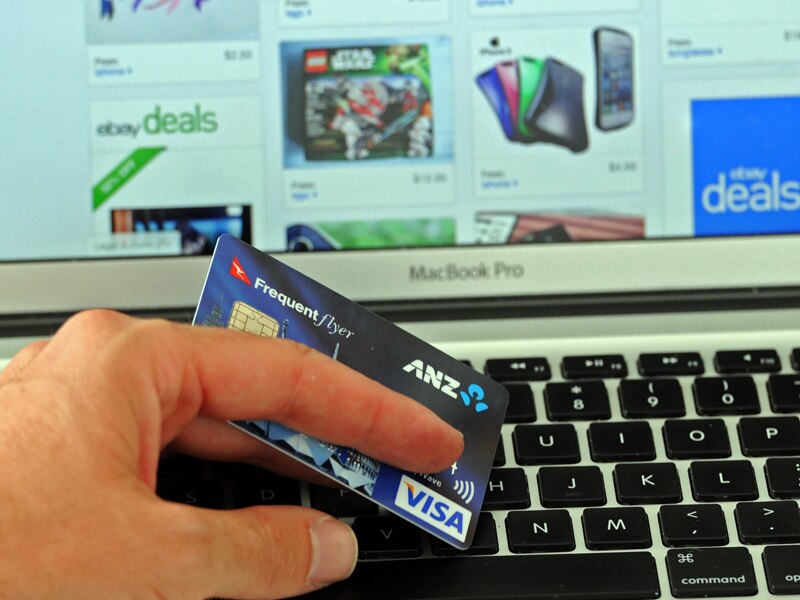 A credit card is held in front an online shopping site