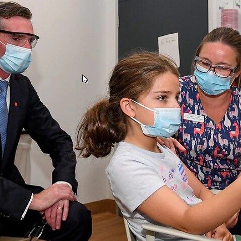NSW Premier Dominic Perrottet watches on as Ines Panagopailos, 8, receives her first dose of the COVID-19 vaccination at the Sydney Children’s Hospital. 