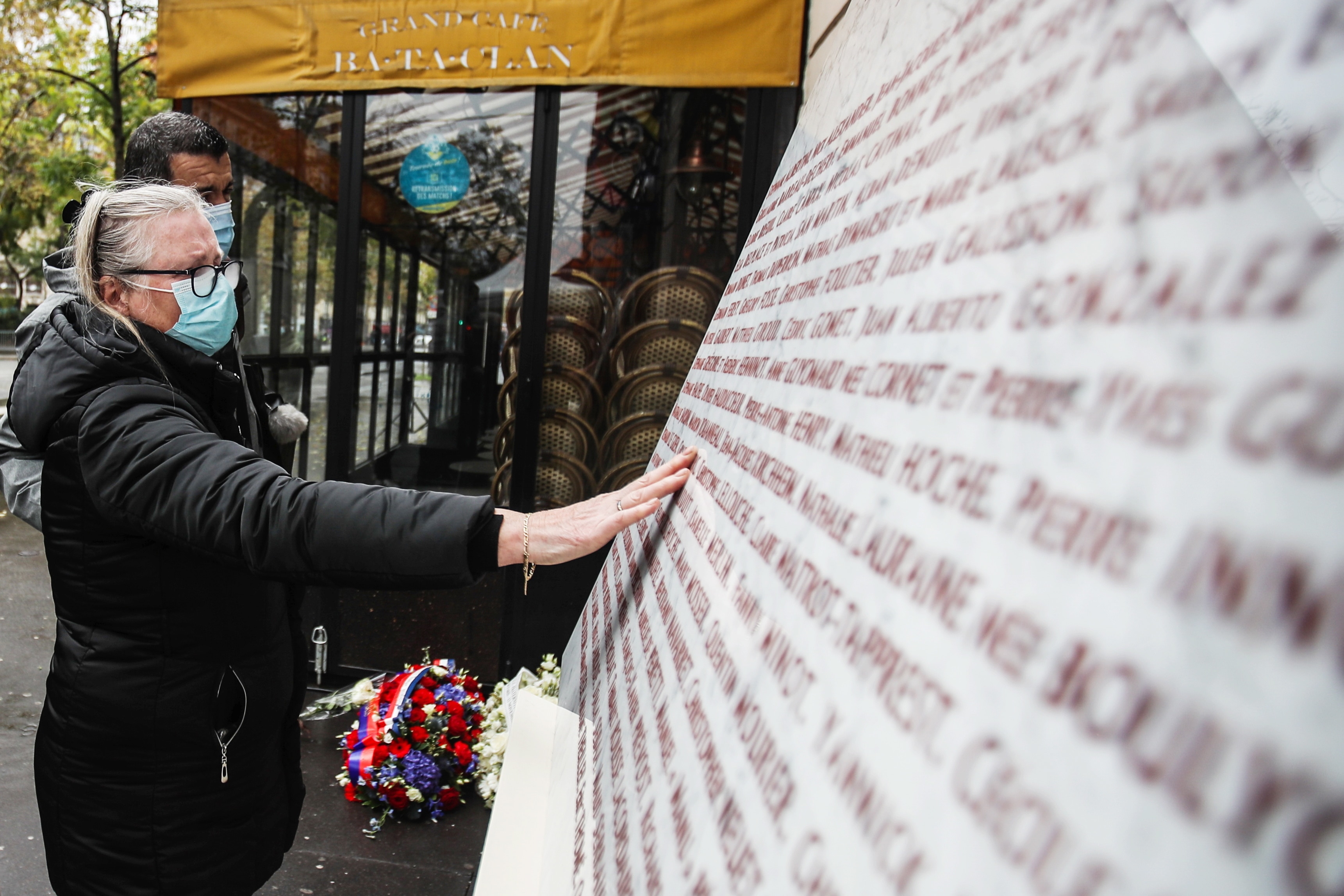 A woman touches the memorial stone after she put flowers outside the Bataclan concert venue, a site of the attacks, in Paris, France, 13 November 2020.