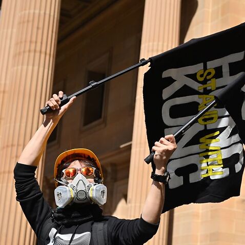 A supporter of the Hong Kong pro-democracy protesters waves flags during a demonstration as part of the global 