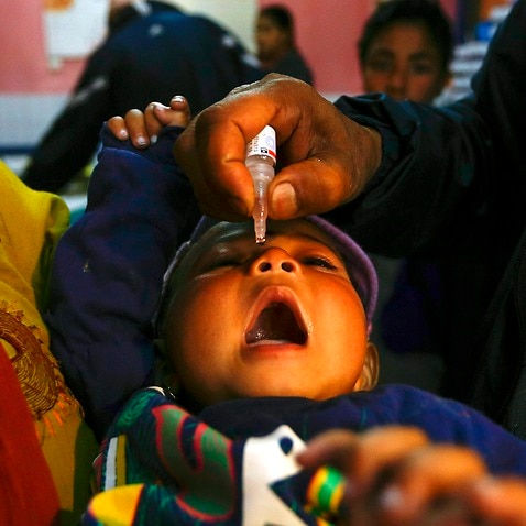 A Nepali child receives polio vaccination drops from a medical volunteer during a daily immunisation programme at Prashuti maternity hospital in Kathmandu, Nepal, 28 March 2014. (EPA/NARENDRA SHRESTHA)