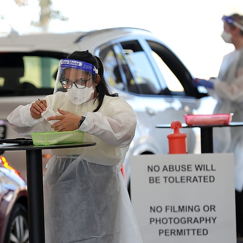 A health worker is seen as members of the public are seen queuing in their cars at a drive-through COVID-19 testing site at IPC Health Wyndham Vale, in Melbourne, Wednesday, December 29, 2021.