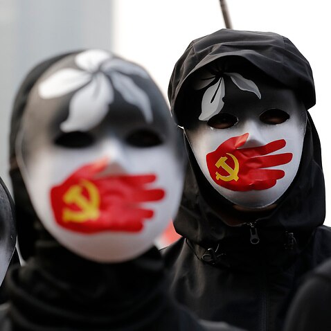 People wearing masks stand during a rally to show support for Uighurs and their fight for human rights.