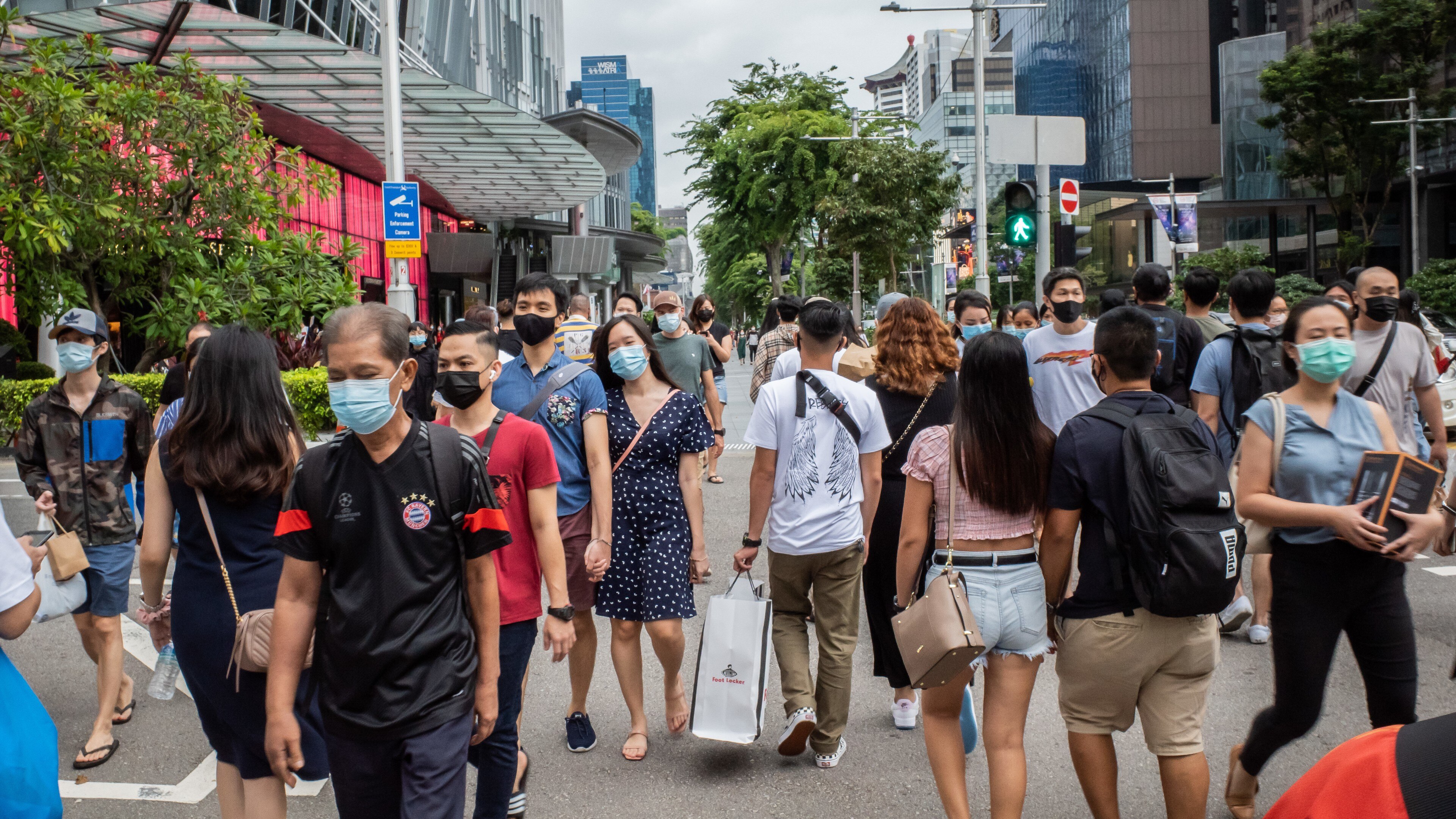 People wearing face masks as a preventive measure against the spread of covid-19 walk along Orchard Road, a famous shopping district in Singapore.