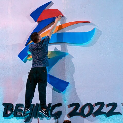 A crew member leaps to fix a logo for the 2022 Beijing Winter Olympics in Beijing.