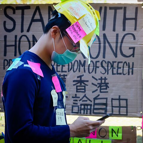 A supporter of the Hong Kong pro-democracy protests, seen covered in sticky notes, standing in front of makeshift 