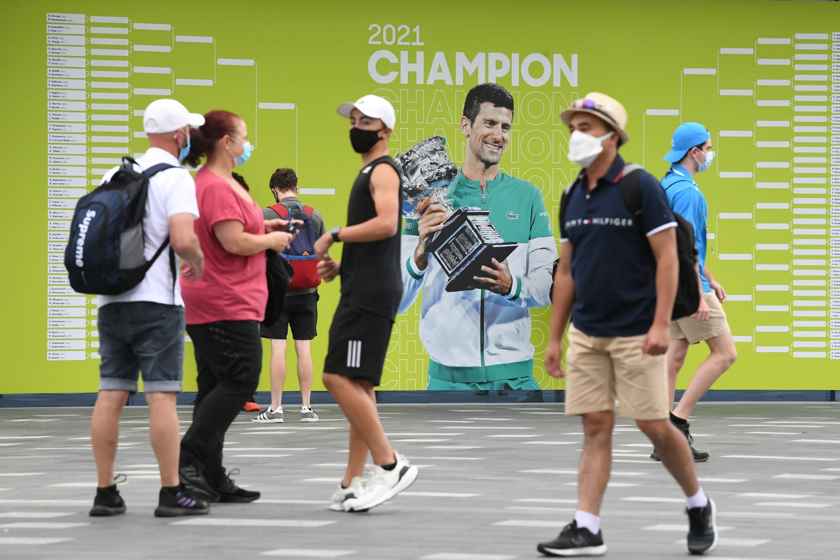 Spectators are seen walking past a picture of Novak Djokovic on Day 1 of the Australian Open Tennis Tournament at Melbourne Park