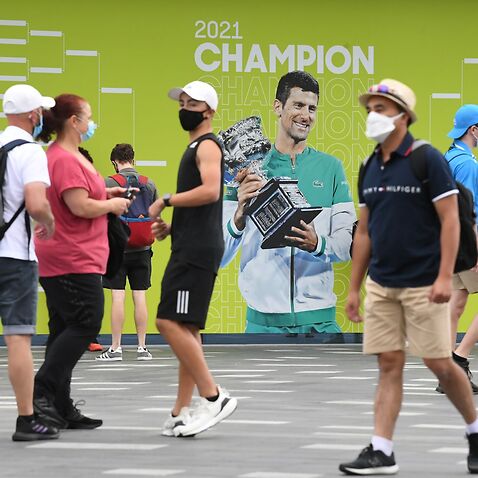 Spectators are seen walking past a picture of Novak Djokovic on Day 1 of the Australian Open Tennis Tournament at Melbourne Park
