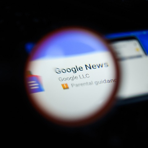 Google News app is seen trough a magnifying glass on an