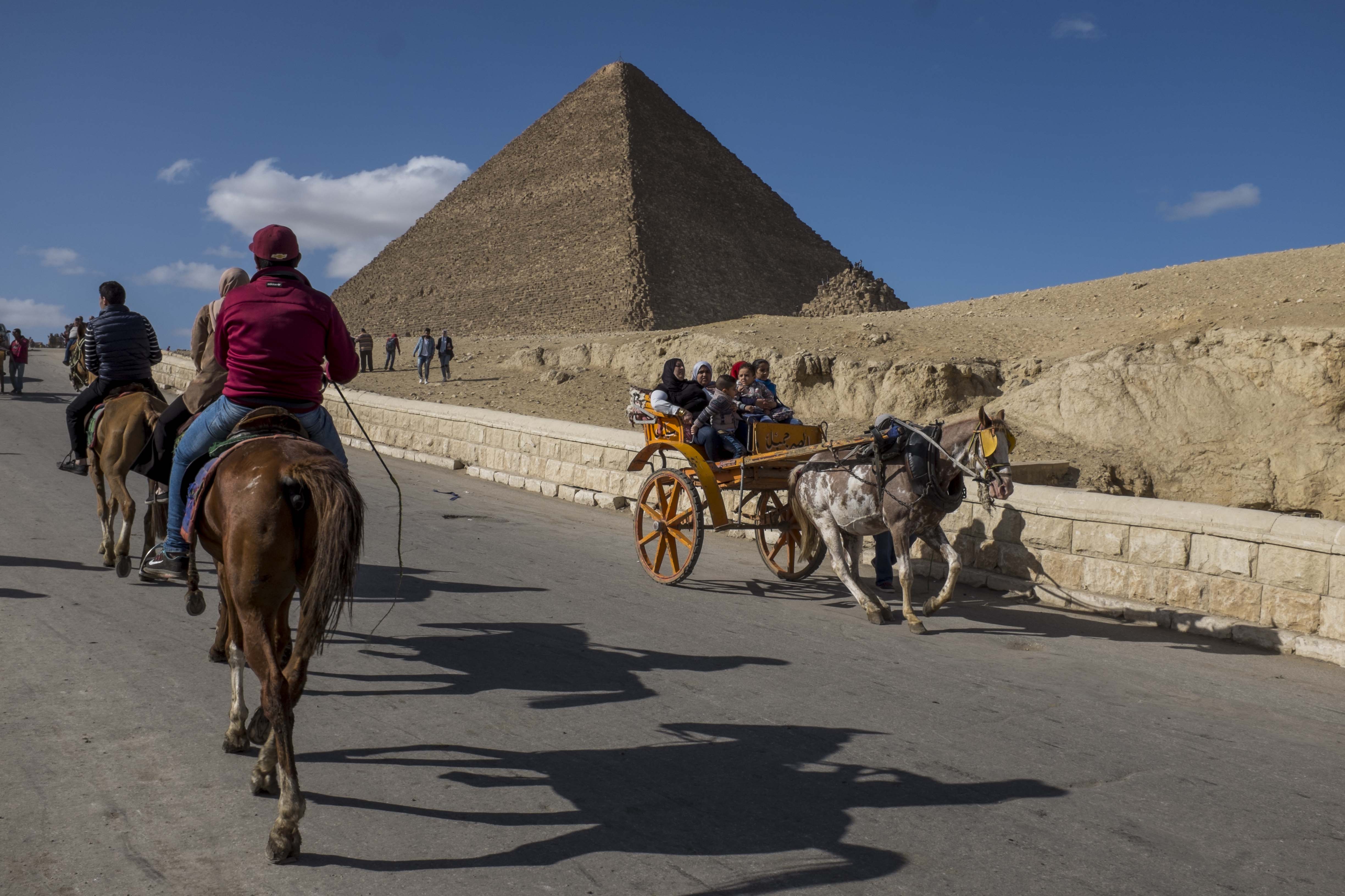 Tourists ride on horses and carriages near the Egyptian pyramids. Tourists ride on horses and carriages near the Egyptian pyramids.