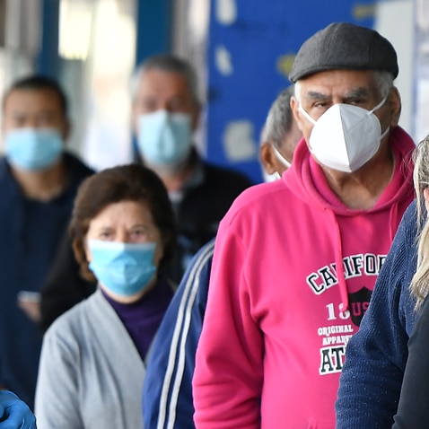 People wearing face masks wait outside a bank at Campsie in Sydney, August 19, 2021.