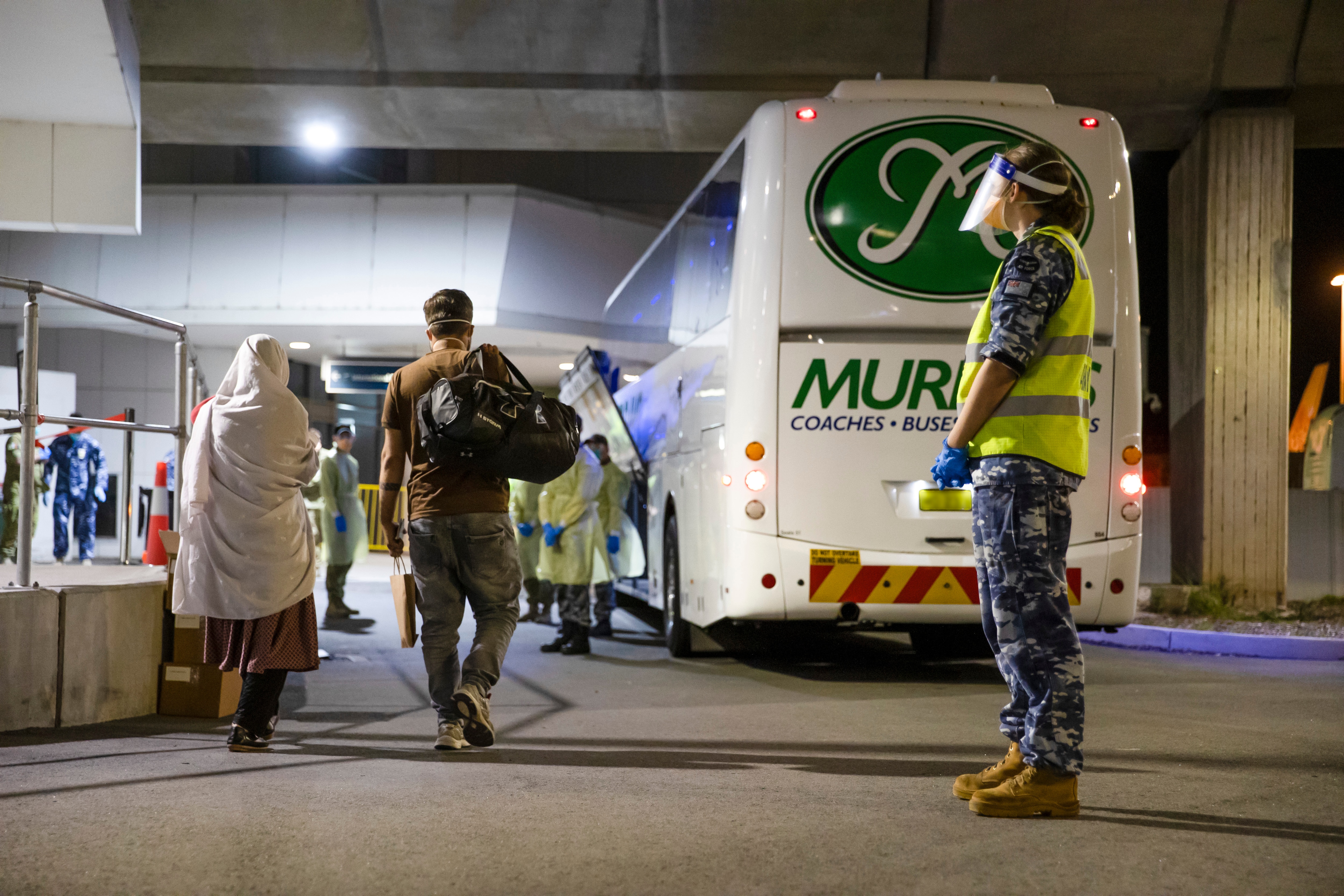 Australian citizens and visa holders evacuated from Afghanistan are assisted off their flight. 