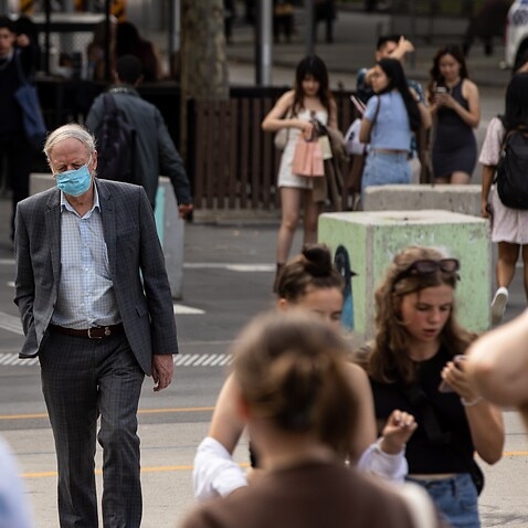 A man wears a face mask as he crosses Flinders Street in Melbourne, Sunday, March 20, 2022. (AAP Image/Diego Fedele) NO ARCHIVING