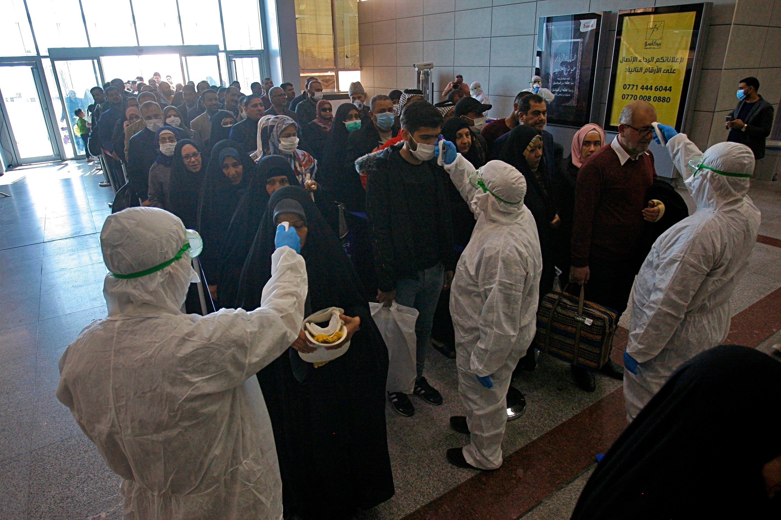 FILE - In this Friday, Feb. 21, 2020, file photo, medical staff check passengers arriving from Iran in the airport in Najaf, Iraq. Coronavirus-infected travelers from Iran already have been discovered in Lebanon and Canada. (AP Photo/Anmar Khalil, File)