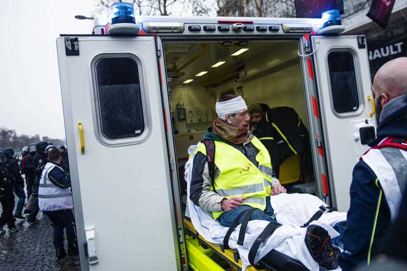 A 'Gilets Jaunes' ('Yellow Vest’) protester treated by paramedics after being injured by riot police in the Champs Elysees Avenu