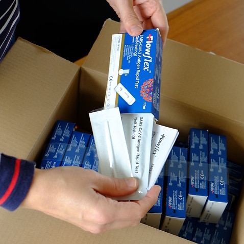 Illustration picture shows  a woman receiving and unboxing a postal package with FlowFlex SARS-CoV-2 Antigen Rapid Tests for self-testing. 