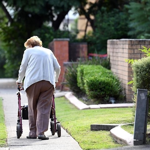 An elderly woman uses a mobility walker