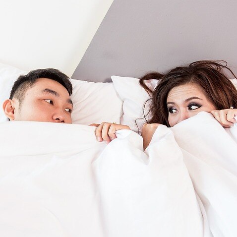Image of a couple looking nervous in bed
