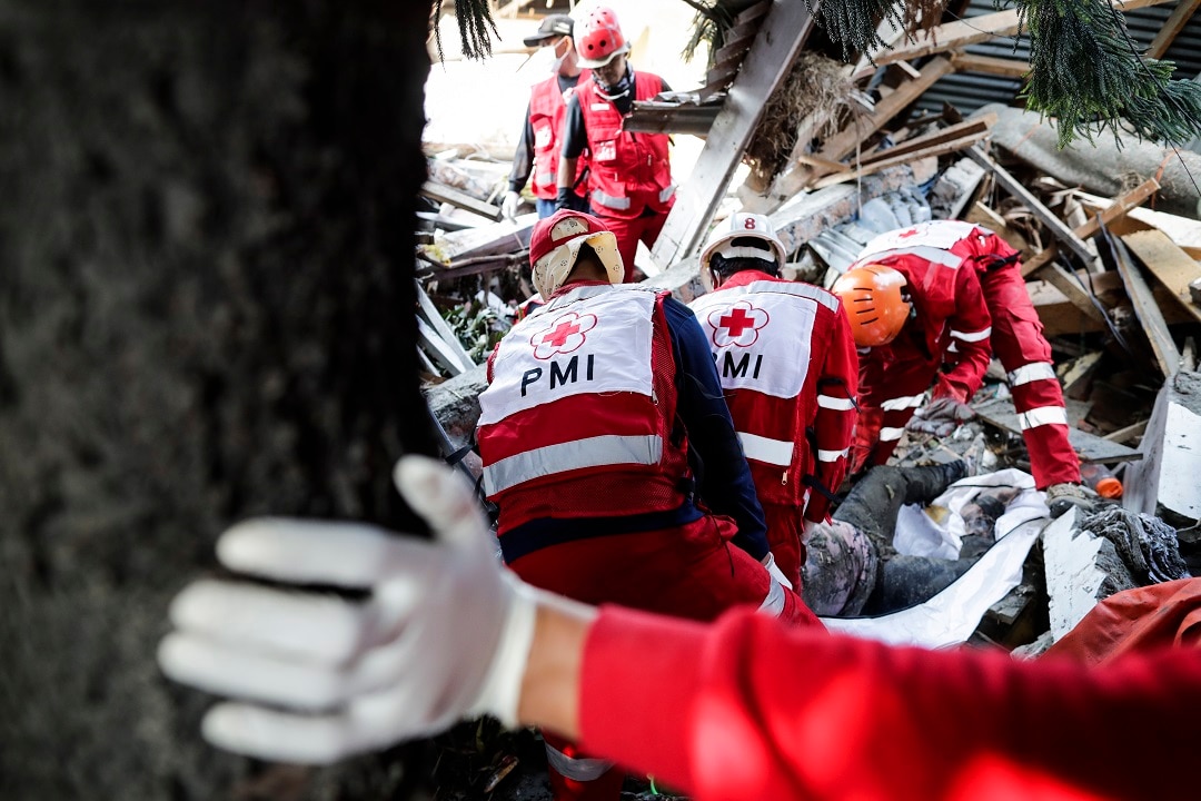Members of the Indonesian Red Cross search for bodies in a collapsed house at Talise beach in Palu.