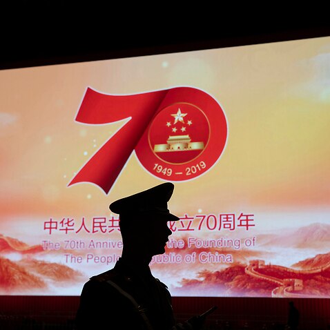 A Chinese paramilitary policeman is silhouetted by a display showing the upcoming 70th anniversary of the Founding of the People's Republic of China in Beijing