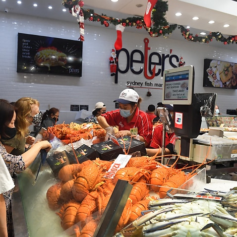 Assistants serve customers buying seafood for Christmas at Sydney Fish Market in Pyrmont, Sydney, Friday, December 24, 2021. The Sydney Fish Market's 36-Hour Seafood Marathon has begun in the lead up to Christmas. (AAP Image/Mick Tsikas) NO ARCHIVING