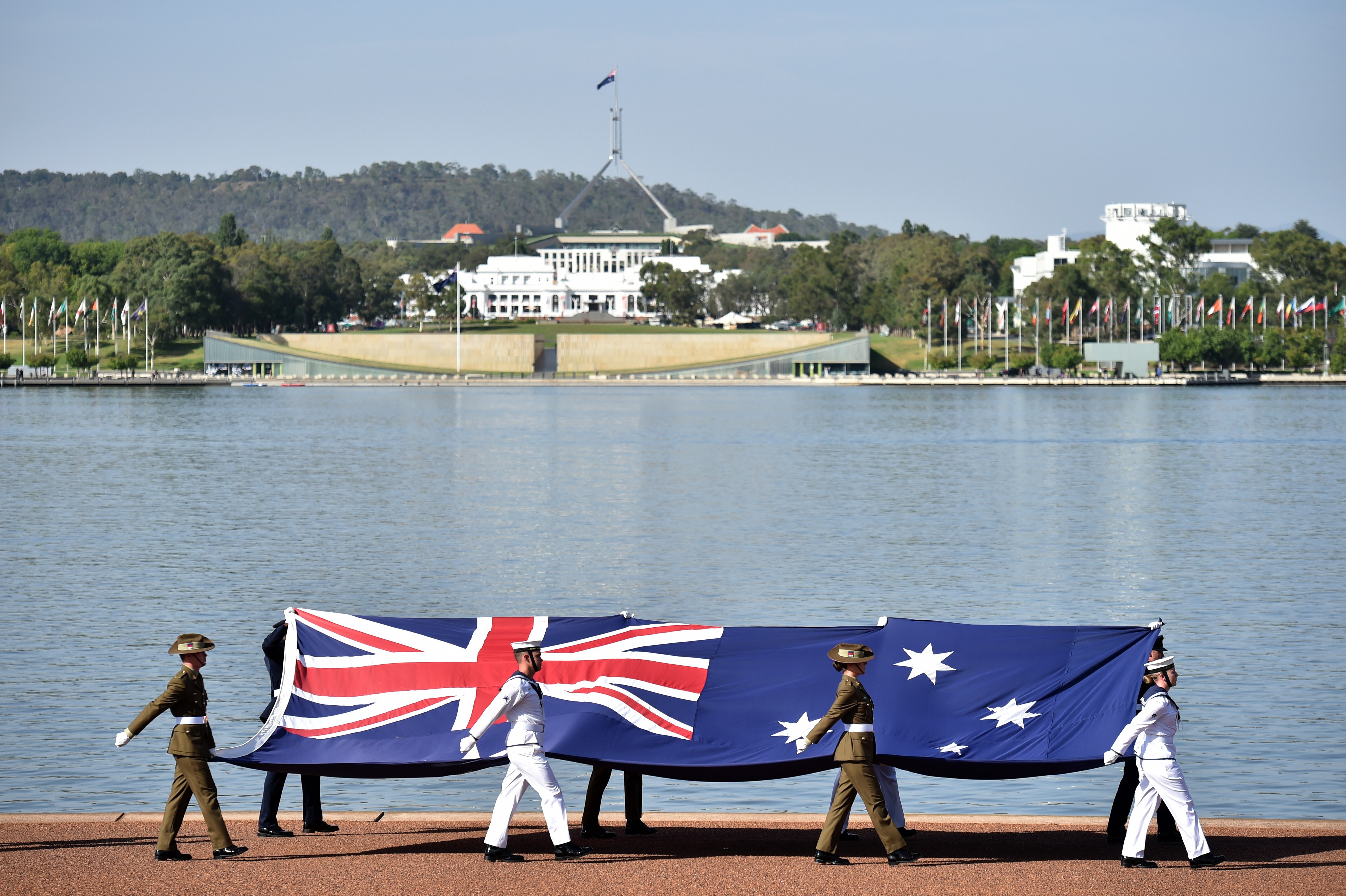 Defence personnel march past with the Australian flag at an Australia Day Citizenship Ceremony and Flag Raising event in Canberra, Saturday, January 26, 2019. (AAP Image/Mick Tsikas)
