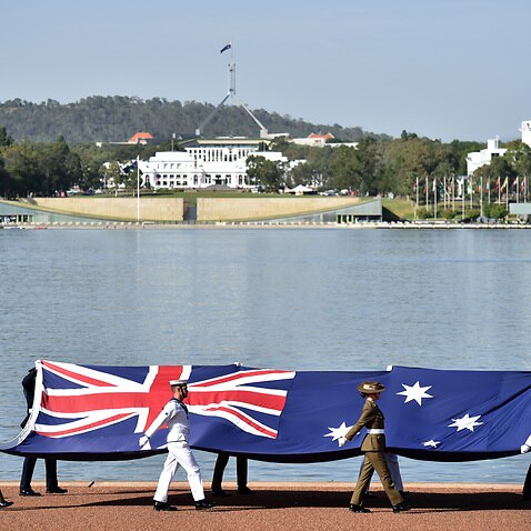 Defence personnel march past with the Australian flag at an Australia Day Citizenship Ceremony and Flag Raising event in Canberra, Saturday, January 26, 2019. (AAP Image/Mick Tsikas)