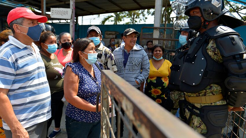 Angehörige von Häftlingen warten auf Informationen, während Soldaten am 30. September 2021 vor dem Gefängnis Guayas 1 in Guayaquil, Ecuador, Wache halten.