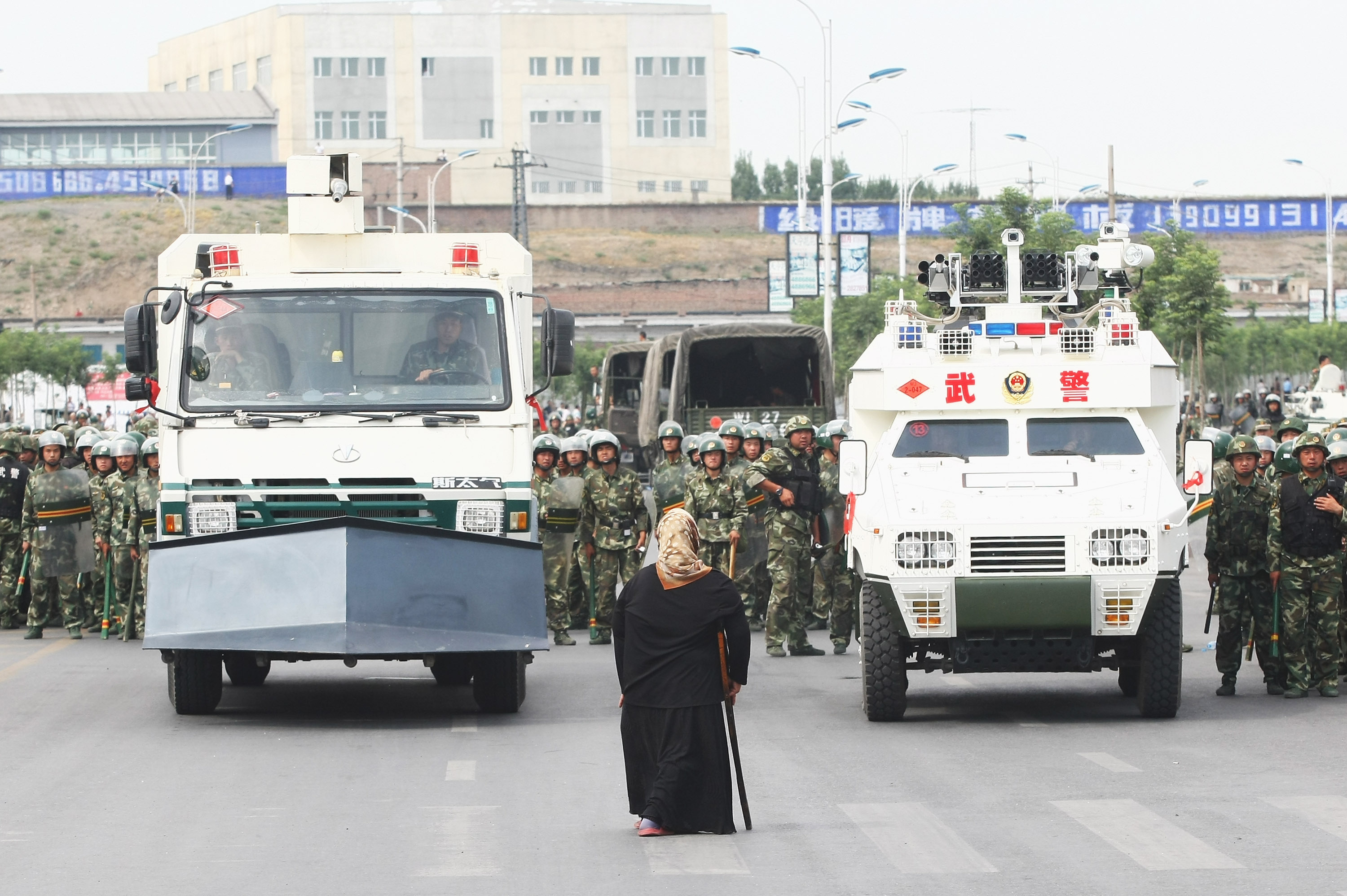 A Uighur woman protests in front of policemen and riot vehicles on July 7, 2009 in Urumqi, the capital of Xinjiang. Riots Occur In China's Urumqi Ethnic Region