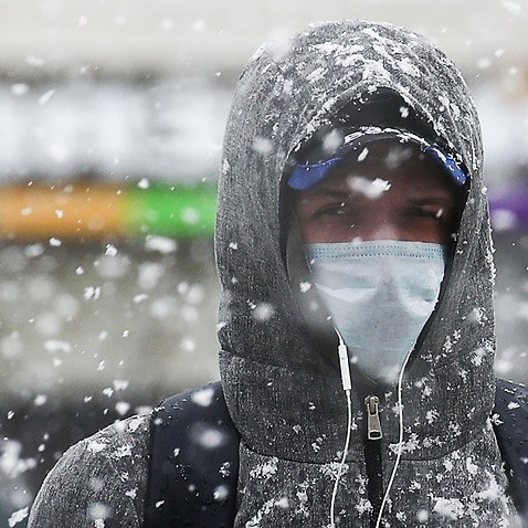 A man seen in a street during a snowfall.