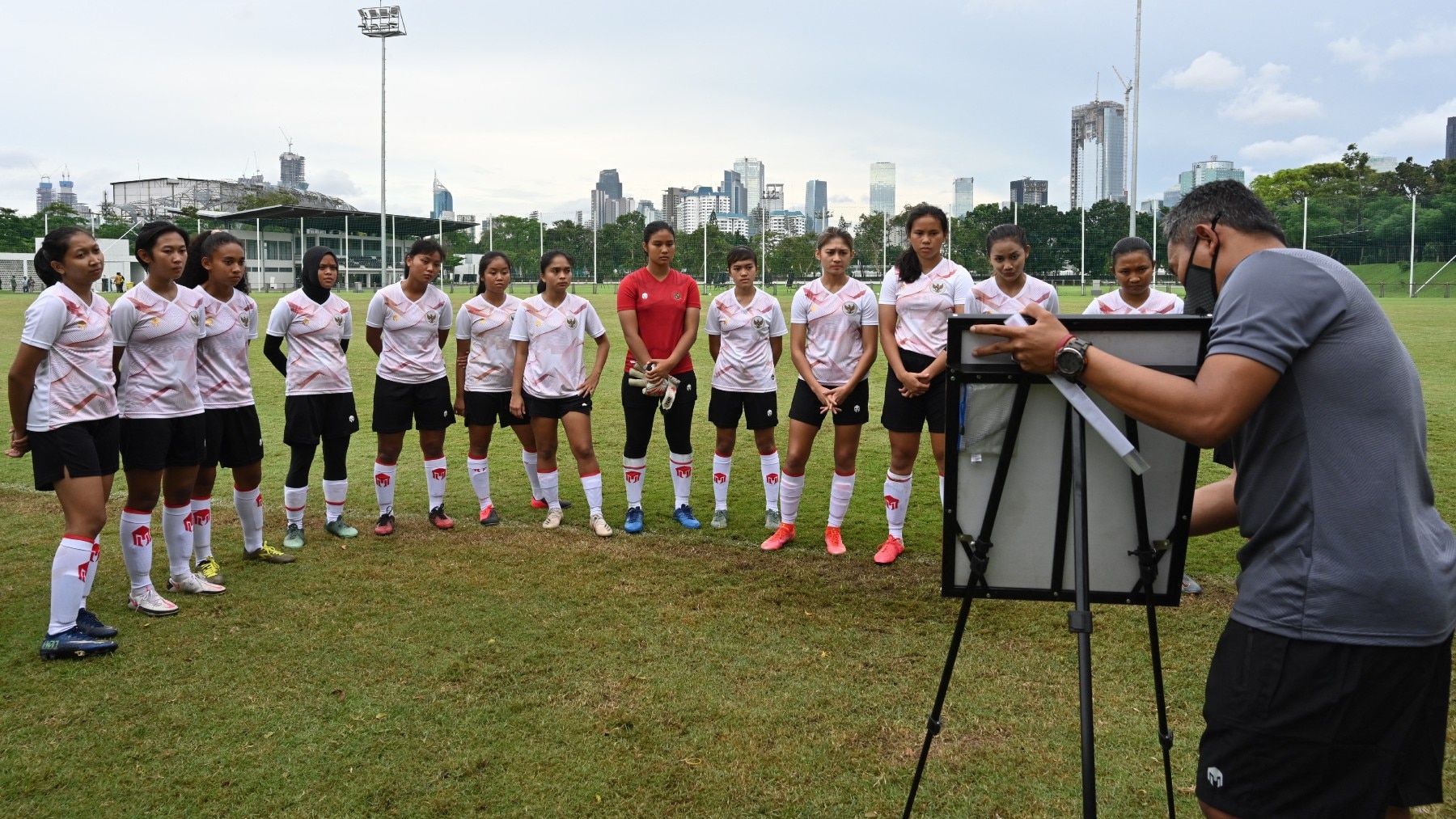 Members of Indonesia's women's national football team listen to coach Rudi Eka (R).