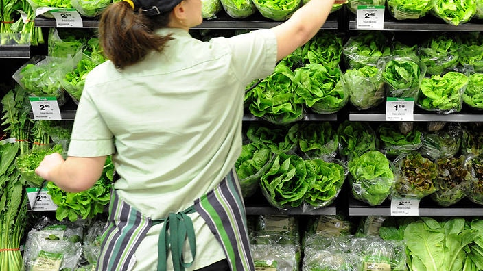An employee arranges vegetables on display inside a Woolworths grocery store in Brisbane