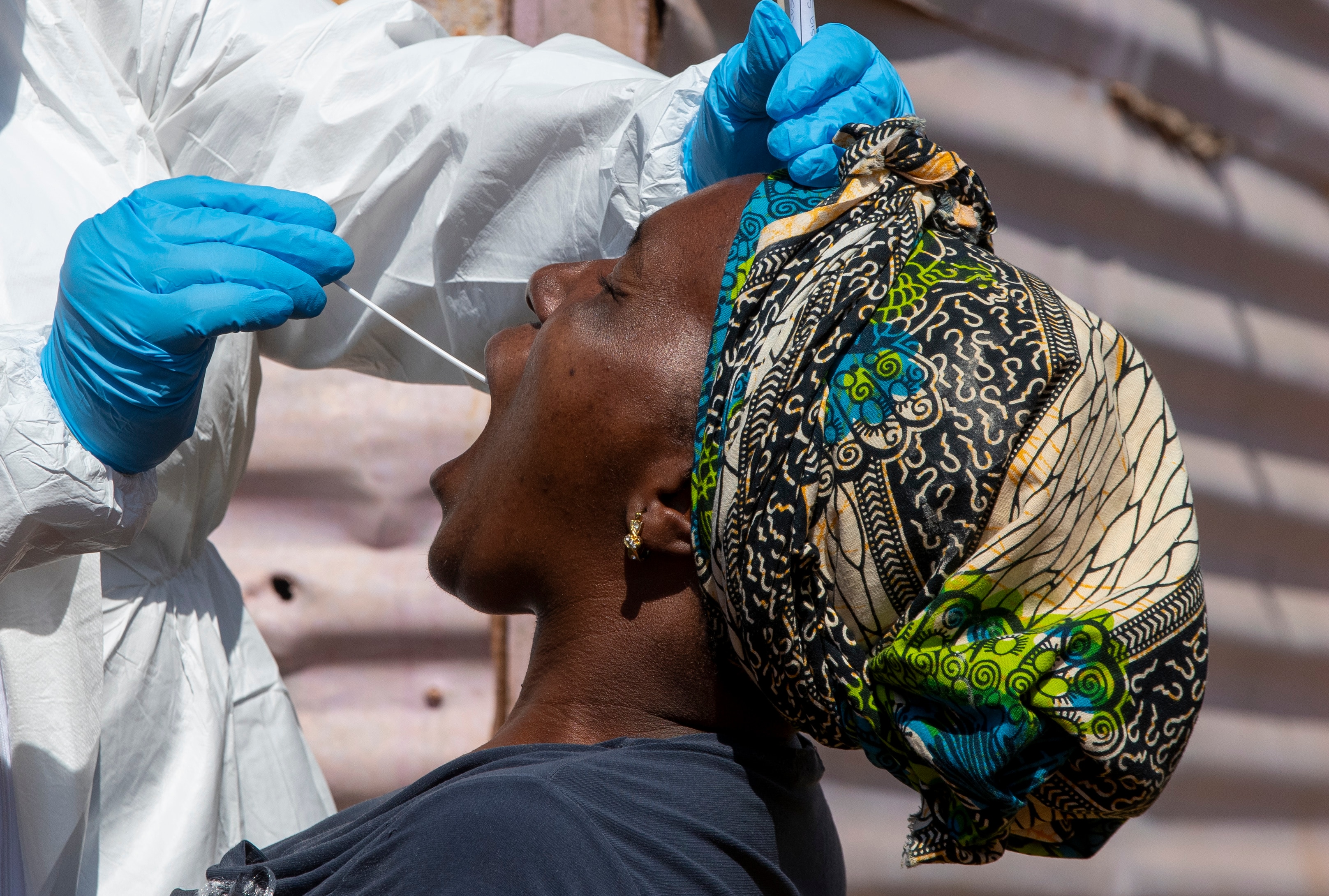 A woman opens her mouth for a heath worker to collect a sample for coronavirus testing in South Africa.