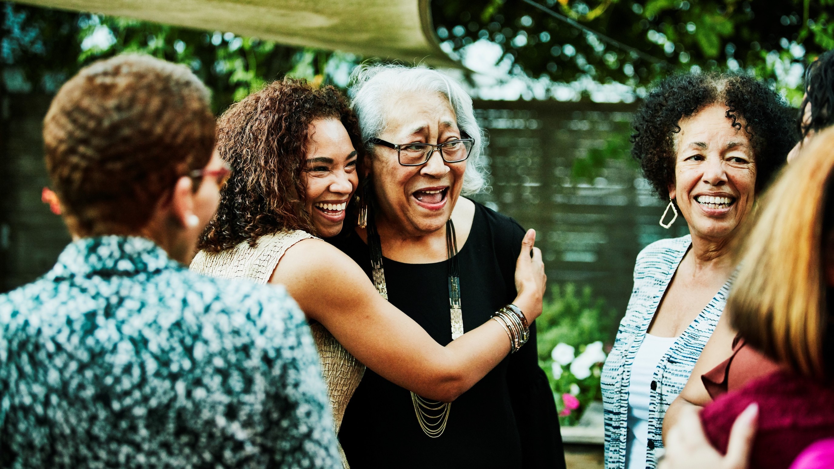 Daughter embracing mother after outdoor family dinner party Daughter embracing senior mother after outdoor family dinner party
