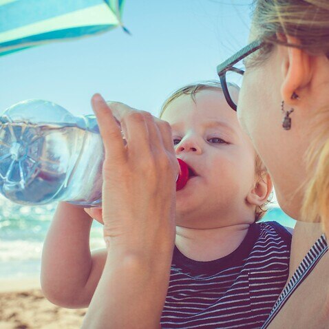 Bebê bebe água na praia