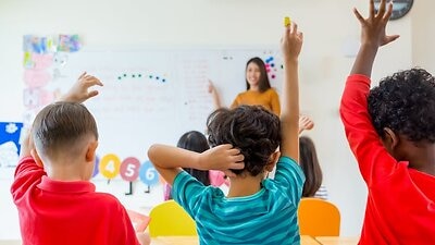 Rear View Of Students Sitting With Teacher