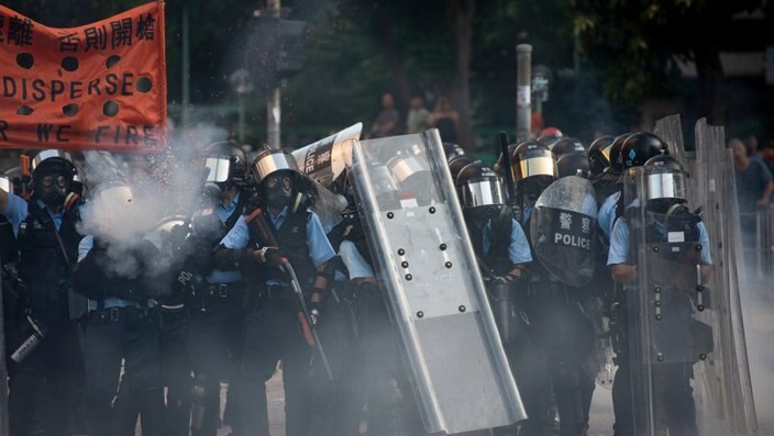 Riot police officers fire tear gas and rubber bullets towards the anti-government protesters during the demonstration.