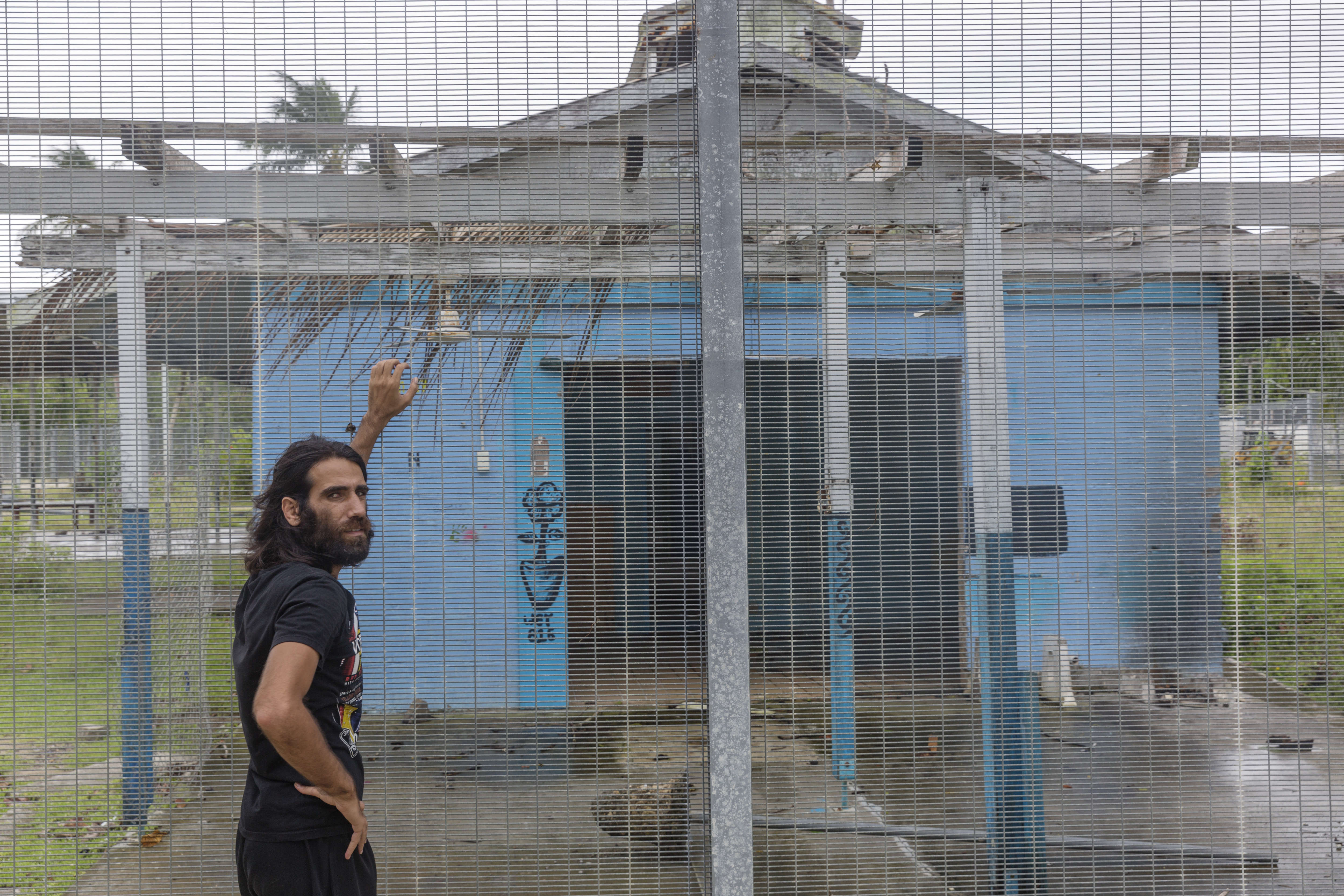 Asylum seeker Behrouz Boochani stands outside the  abandoned naval base on Manus Island where he and others were housed.