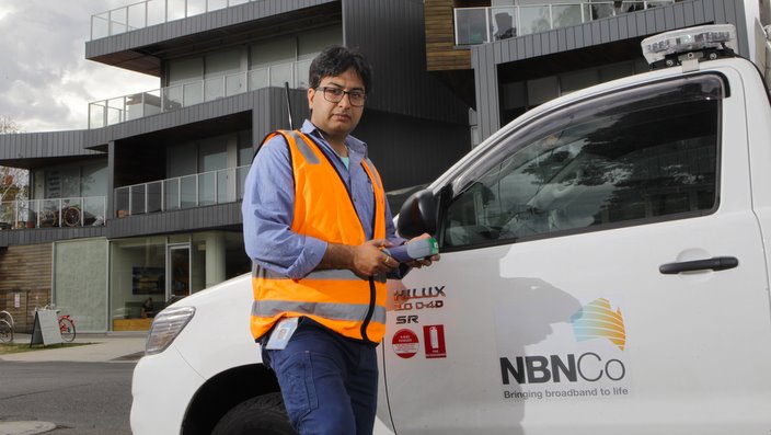 NBN technician in front of an apartment block that has been connected to the National Broadband Network
