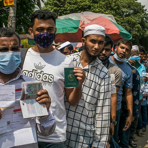 Migrant worker standing in a line in front of Dhaka Medical College Hospital displays his passport as he waits for Covid-19 vaccination.