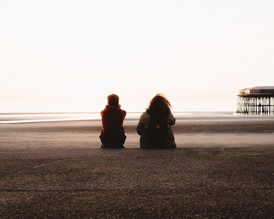 Two teenagers talking on a beach