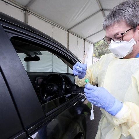 A nurse takes a sample from a driver at a COVID-19 testing facility.