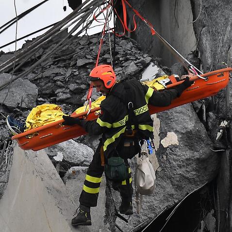 Firefighters rescue a person from the rubble of the collapsed Morandi highway bridge in Genoa, northern Italy, Tuesday, Aug. 14, 2018. 