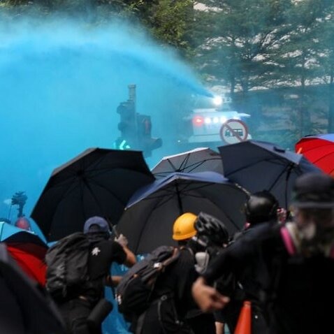 Police fire water canon toward anti-government protesters.